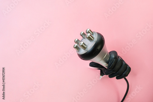 RF lifting hardware massage on a pink background. hand in a black glove with an apparatus. photo