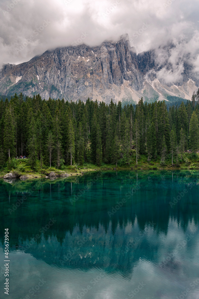 Extremely clear water with reflection in Carezza lake in South Tyrol, Italy. Surrounded by green , rich forest and dolomite mountains, Alps.