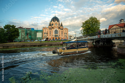 Принти на полотні Summer panorama with Synagogue in Kaliningrad and moving boat in chanal and brid