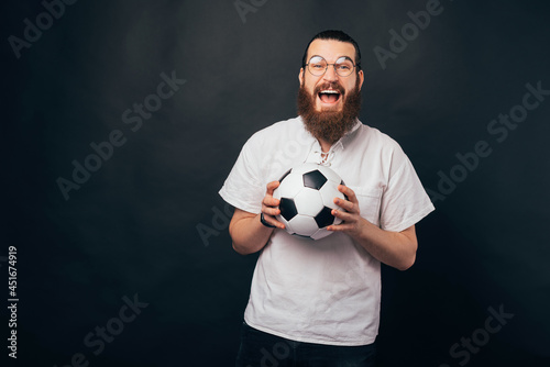 Excited bearded man is holding a soccer or football ball.