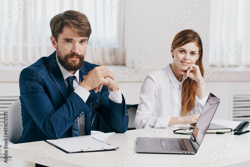 business man and woman talking at the table in front of laptop professionals technology