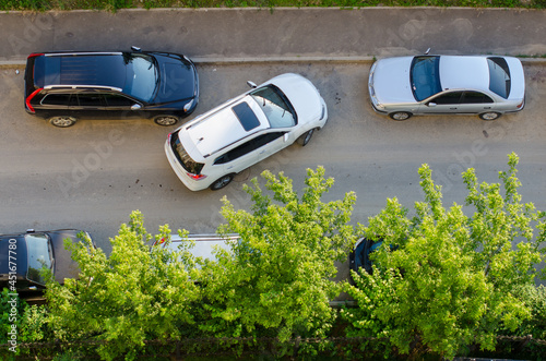 Fotografie The uneasy parking of the white car near black and grey, shot from above