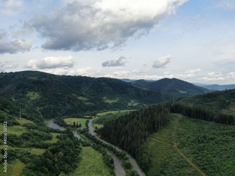 Winding road from high mountain pass, in summer time. Aerial view by drone.