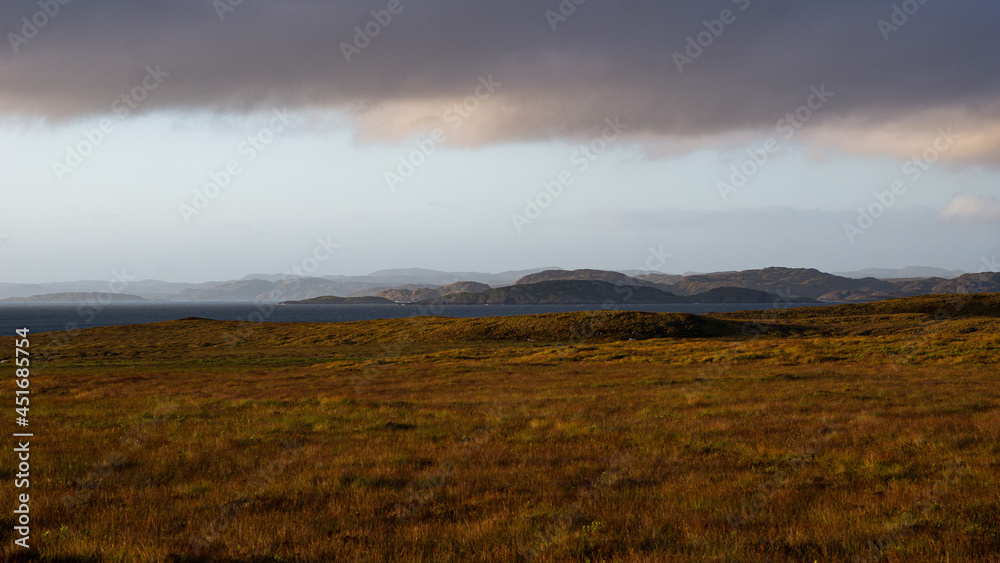 Scottish landscape at sunset with field, sea, mountains and clouds