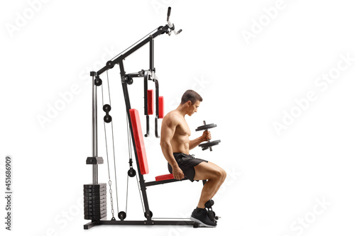 Bodybuilder sitting on a fitness machine and lifting a barbell photo