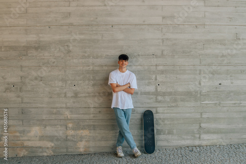 teen boy with skateboard on wall with copy space © carballo