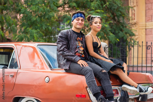 Young couple sitting on a car on the street