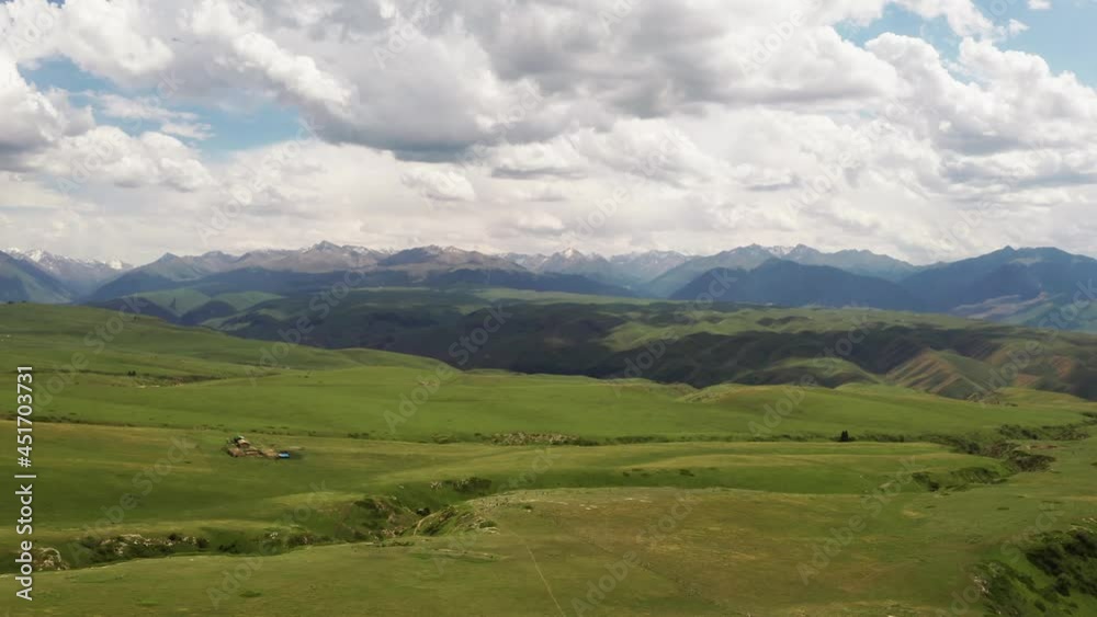 Mountain peaks and grassland are under white clouds. Mountain peaks and grassland are under white clouds.