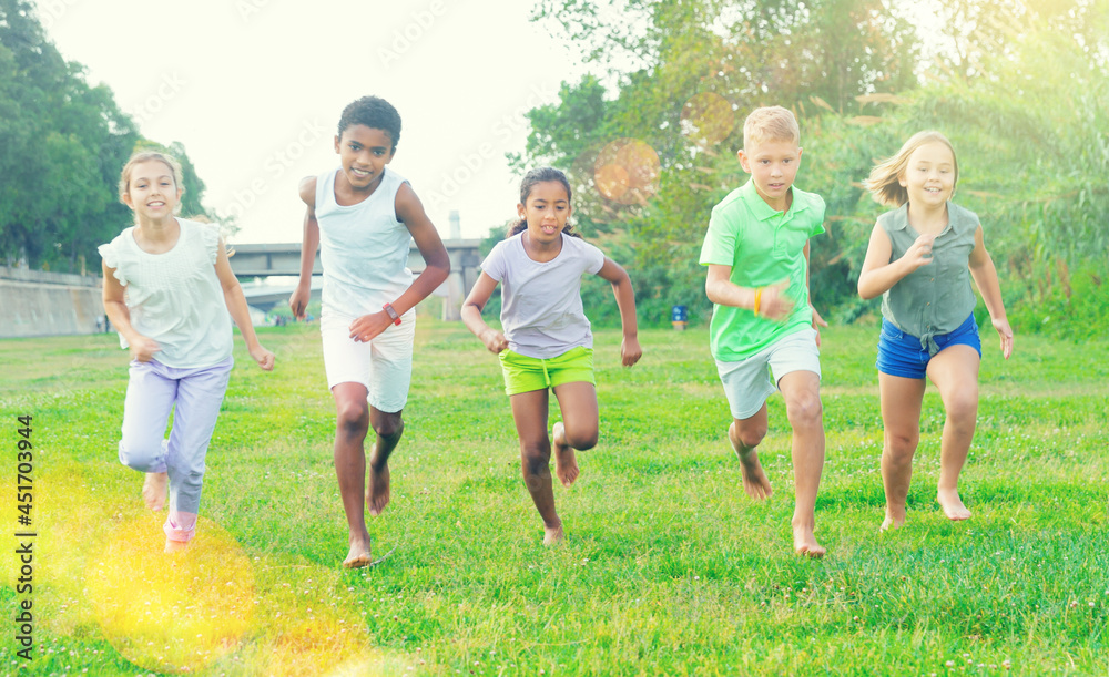 Fototapeta premium Portrait of five smiling kids who are running in race and laughing in park