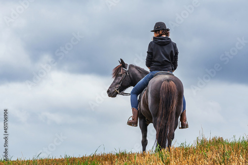 Back side of a young woman and her pony on a stubble field. Text space