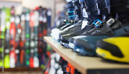 Different new models of boots for alpine skiing on shelves in shop