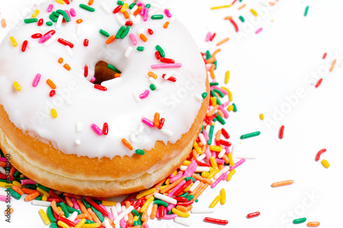 Vanilla frosted donuts with rainbow sprinkles on a white background