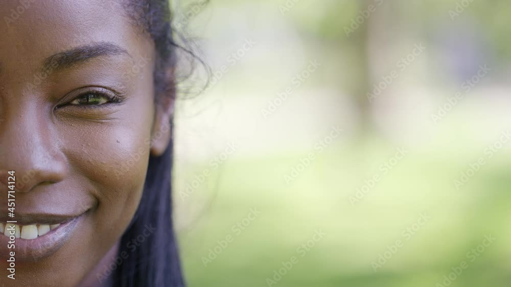 Half face portrait of attractive black female opening her eyes and smiling to camera in slow motion, with space for text Half face portrait of attractive black female opening her eyes and smiling to camera in slow motion, with space for text