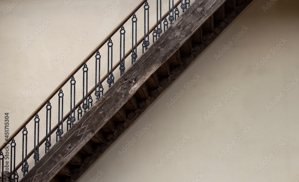 Wooden stairs with iron railings and cream colored walls.