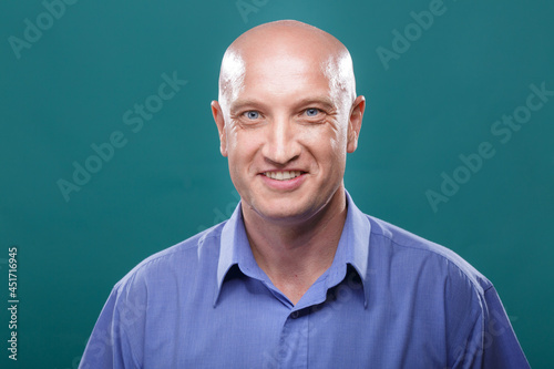 Portrait of a bald man on a blue background. Model in her 40s, blue eyes and a blue shirt. . Smiling facial expression