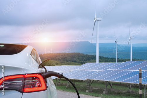 EV Car or electric power car and solar cells for electricity generation,plug of power cable electric supply during charging at ev car. photo