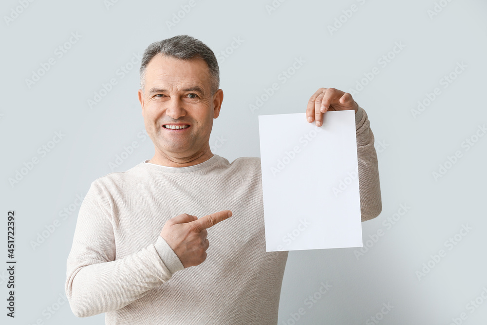 Mature man with blank poster on light background Mature man with blank poster on light background