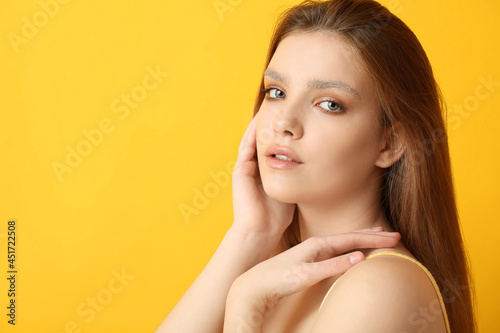 Beautiful young woman with dyed eyebrows on color background