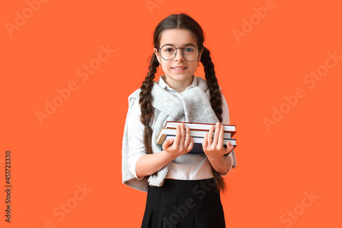 Cute little school girl with books on color background © Pixel-Shot