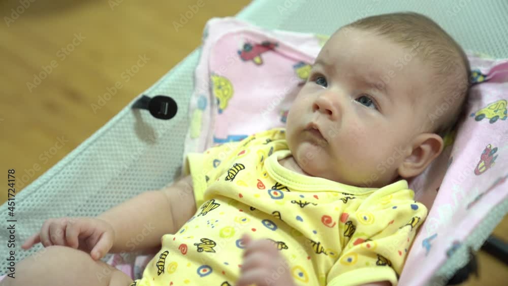 Newborn baby swinging and jerking his arms in a baby rocking chair