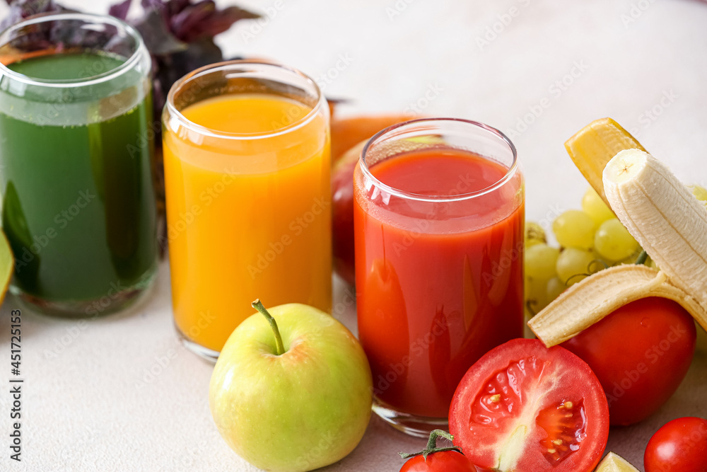 Glasses with healthy juice, fruits and vegetables on light background Glasses with healthy juice, fruits and vegetables on light background