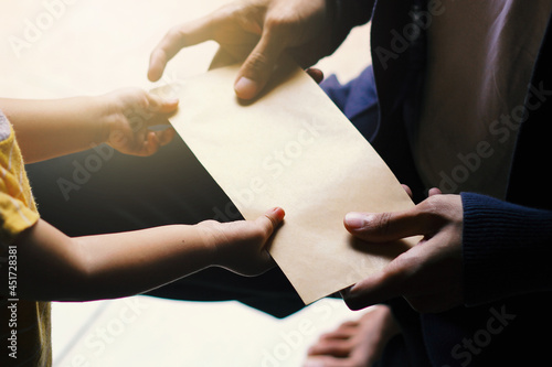 A Young man is giving an envelope to a little girl. 