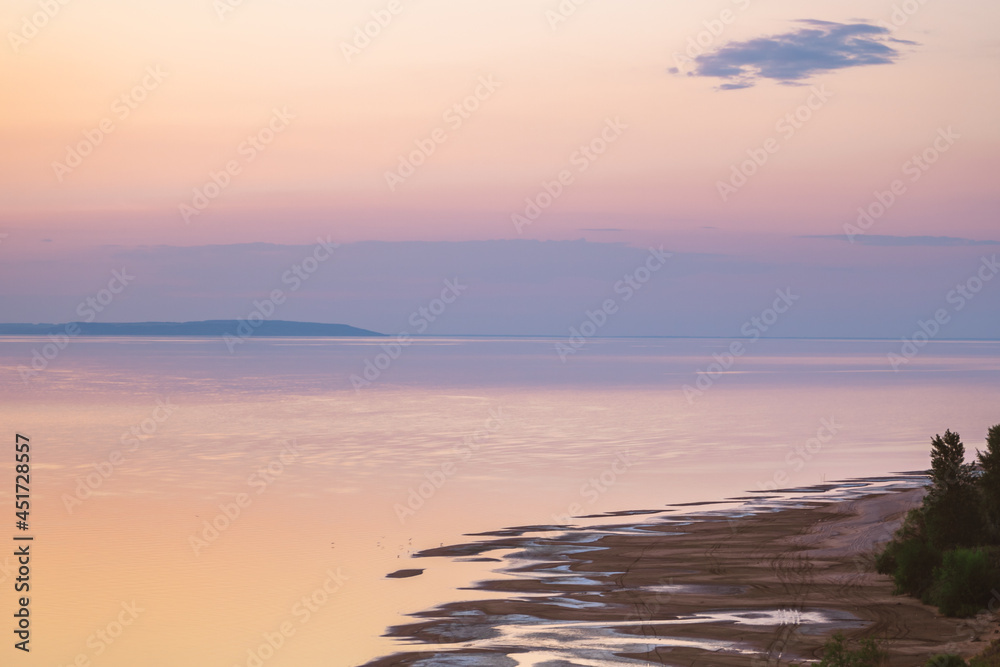 Beautiful gentle sky over the sea during sunset. Pink romantic summer shades of the sky. Sandy beach.