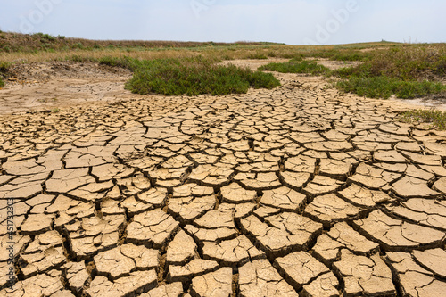Landscape with dry cracked ground in the foreground in a hot area. Selective focus in the foreground