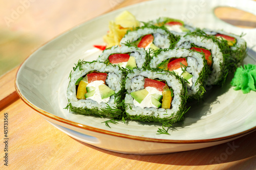 Vegeterian sushi roll with dill and vegetables on wooden background