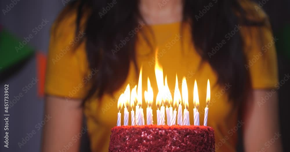 A close-up portrait of an attractive brunette in a yellow dress sitting in front of a birthday cake with candles. She blows out the candles and claps her hands. 4k slow motion 50 fps A close-up portrait of an attractive brunette in a yellow dress sitting in front of a birthday cake with candles. She blows out the candles and claps her hands. 4k slow motion 50 fps