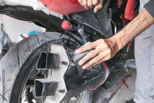 Preparation for painting a motorcycle. Hand in a sandpaper photo