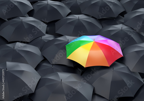 Rainbow colored umbrella among dark ones