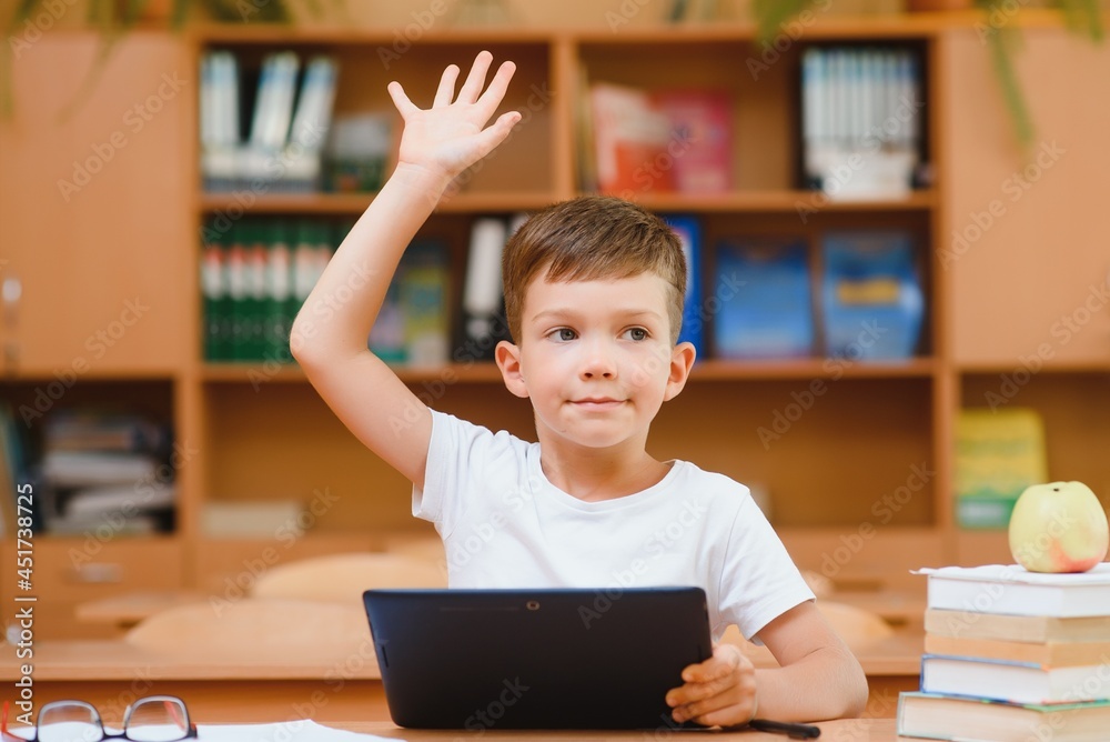 Elementary schoolboy using digital tablet with classmate studying in background at classroom Elementary schoolboy using digital tablet with classmate studying in background at classroom