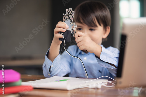 Kid self isolation using tablet for his homework, child playing with robotic arm alone during covid 19 lock down,Home schooling,Social Distance,E-learning online education.
