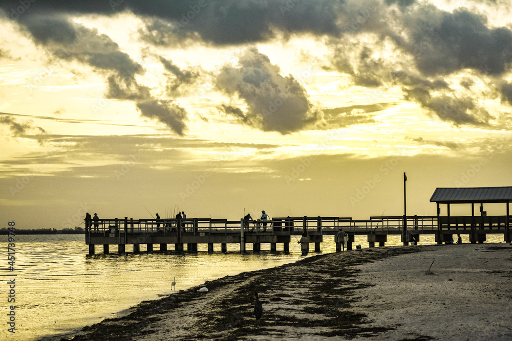 sunset at Sanibel lighthouse park where people are fishing on a dock