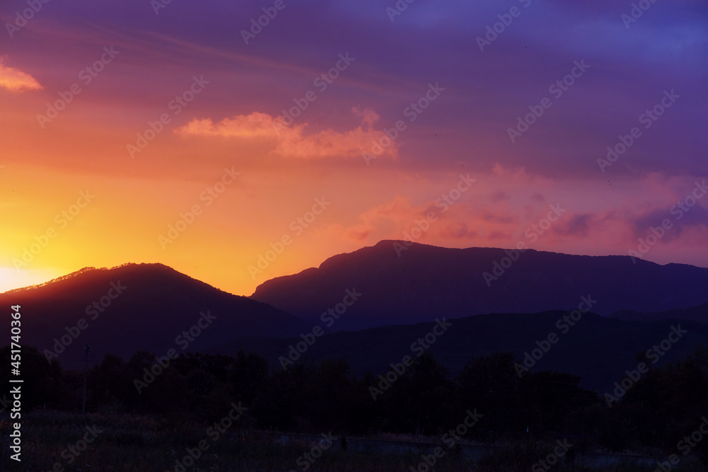 Colorful sunset in shades of pink, purple and orange over the low mountains in Primorsky Krai, Russia. Contrasting defocused background with the silhouette of the mountains