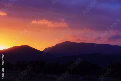 Colorful sunset in shades of pink, purple and orange over the low mountains in Primorsky Krai, Russia. Contrasting defocused background with the silhouette of the mountains