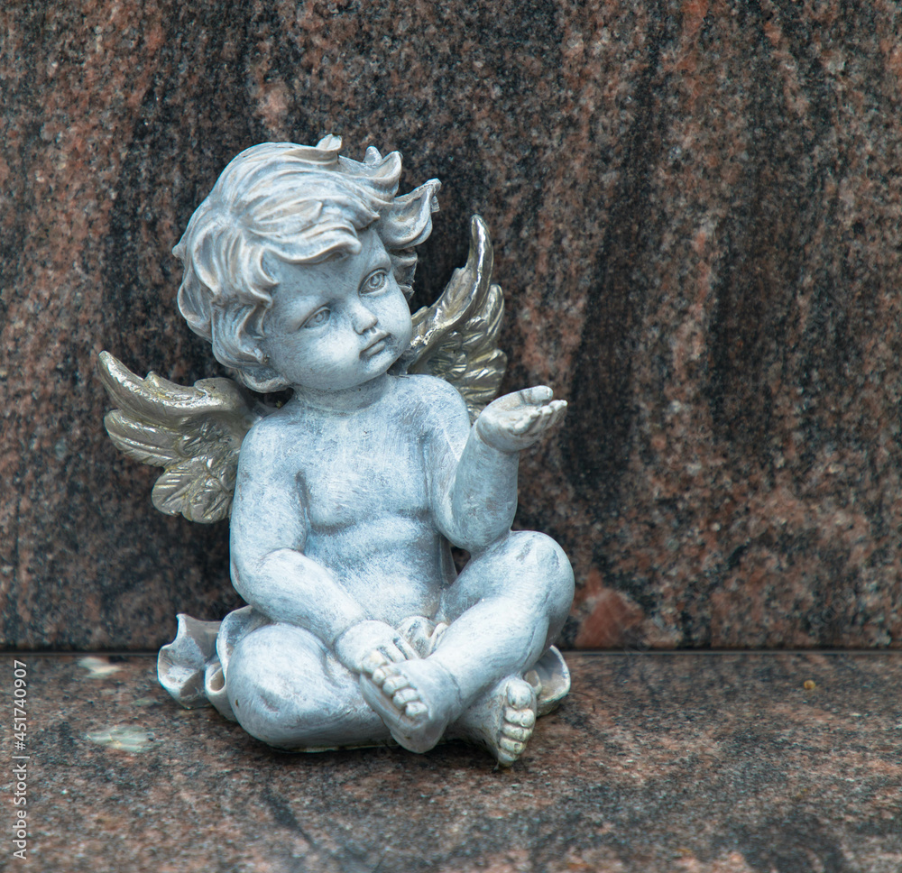 Cemetery scene. Close up of a sad pensive angel sitting on a grave. Pain, fear, end of life. Symbol of the end of human life. Remembrance concept. Cemetery scene. Close up of a sad pensive angel sitting on a grave. Pain, fear, end of life. Symbol of the end of human life. Remembrance concept.