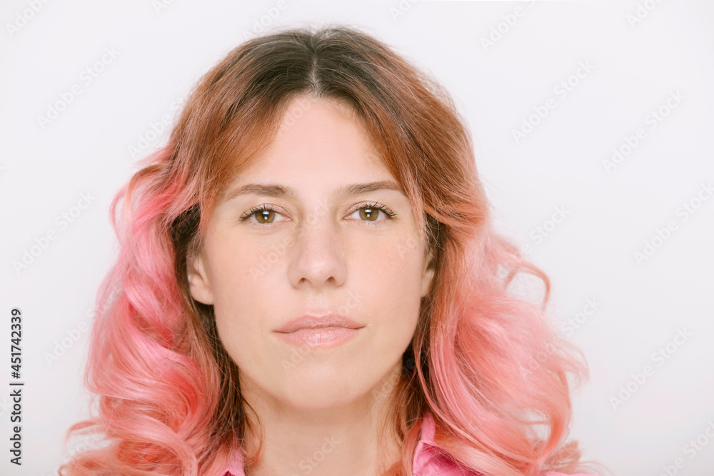 Naklejka premium smiling mature woman with pink hair looking at camera wearing pink dress