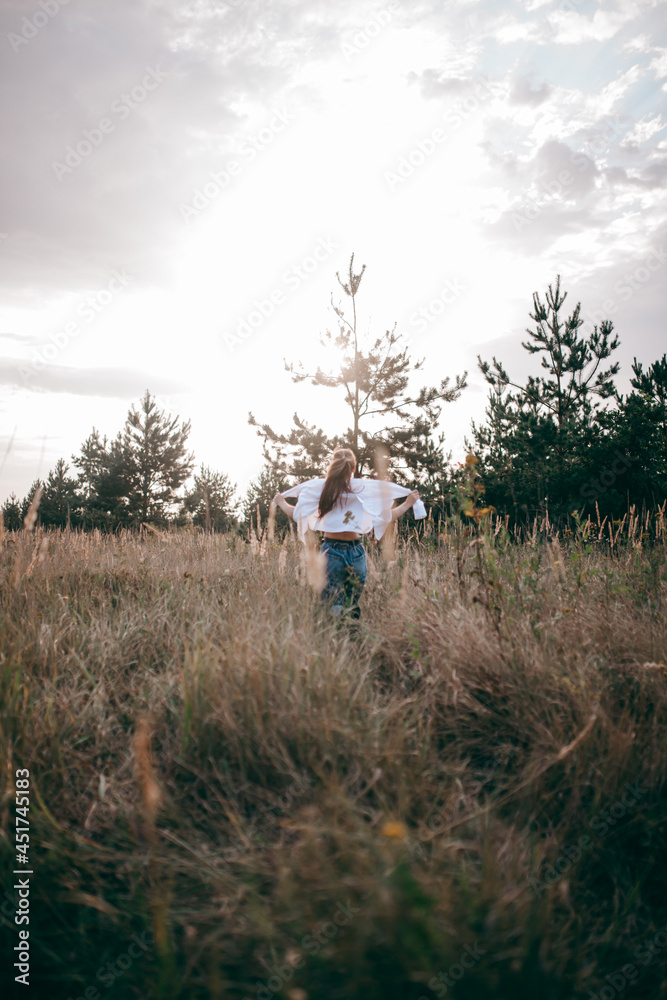 A Free, Happy Woman Enjoying Nature. Pretty Girl Outdoors. The girl runs across the field
