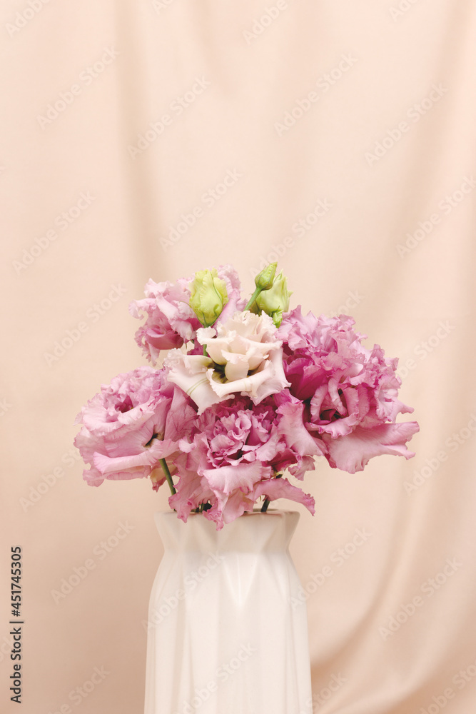 Bouquet of eustoma flowers in vase in front of beige cloth background. Present for 8 March, Mothers Day. Springtime composition with copyspace. Bouquet of eustoma flowers in vase in front of beige cloth background. Present for 8 March, Mothers Day. Springtime composition with copyspace.