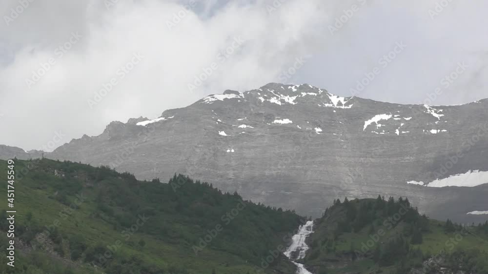The Rocky Mountains With Cascades Flowing Over Forest Hills Under Clouded Sky. - Wide The Rocky Mountains With Cascades Flowing Over Forest Hills Under Clouded Sky. - Wide