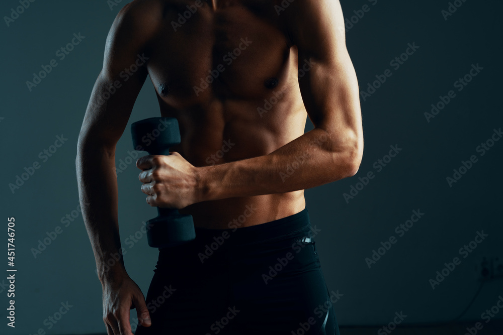 Naklejka premium a man with a pumped up press workout with dumbbells exercises dark background