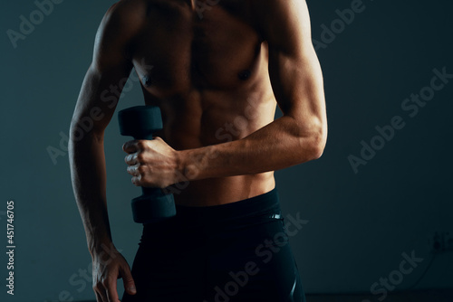 a man with a pumped up press workout with dumbbells exercises dark background