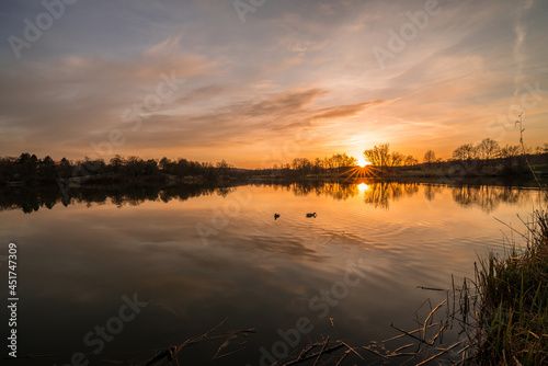 Landschaft und Sonnenuntergang am Ufer im Westpark Donaupark in Regensburg mit Spiegelung des Himmels in dem glatten See mit wundersch  nen dramatisch Farben Farbenspiel mit Wolken  Deutschland