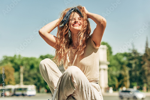 Cheerful young woman smiling broadly enjoying the sunny day. A positive female has a joyful expression while resting outdoors. Mental health concept.