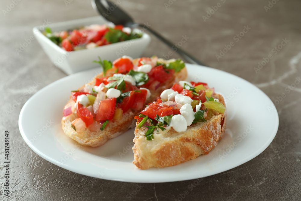Plate with bruschetta snacks on gray textured table
