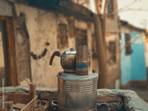 Close-up photo of blackened metal teapot on old samovar stove in the back streets of Ulus, Ankara,  Blurry tumbledown slums on the background. photo