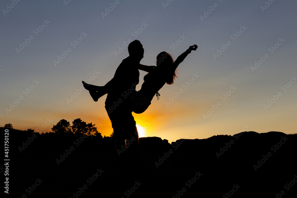 Boy holding girl in his arms at sunset in autumn. Copy space. Backlight. Love.