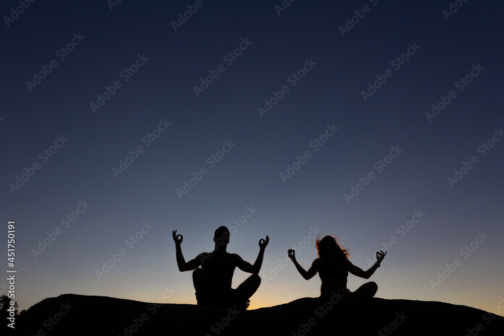 Young couple practicing yoga at sunset. Backlight. Copy space. Young couple practicing yoga at sunset. Backlight. Copy space.